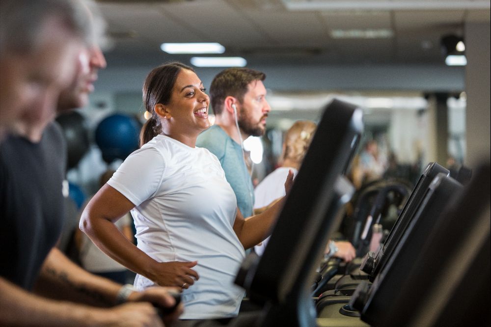 A group of men and women using the treadmills, in the gym.