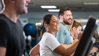 Man and woman laughing on a treadmill at the gym