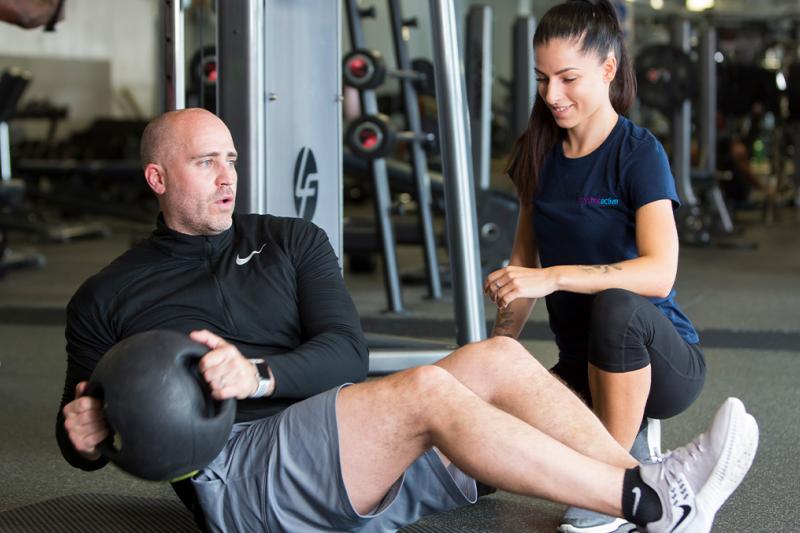 A challenge seeker with a personal trainer working out in the gym