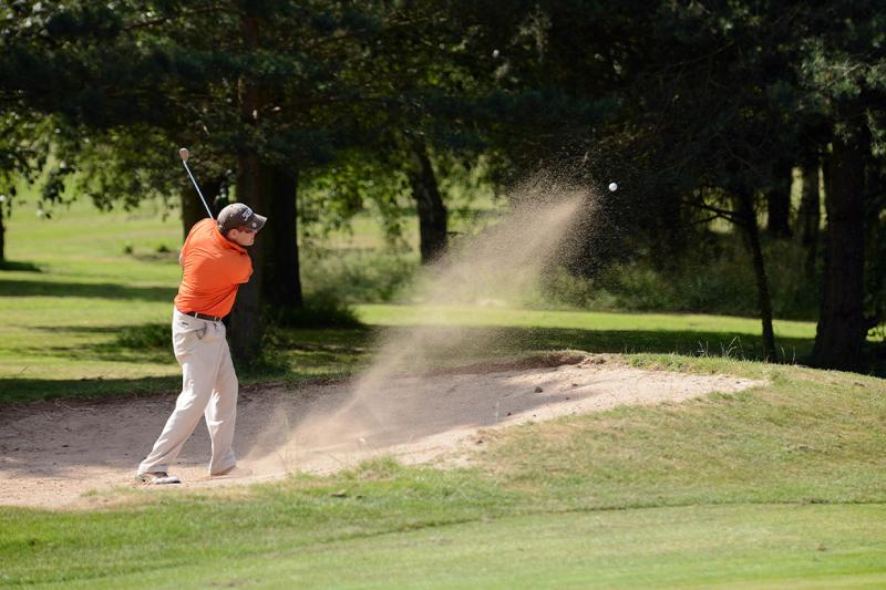 Man hitting a bunker shot on a golf course