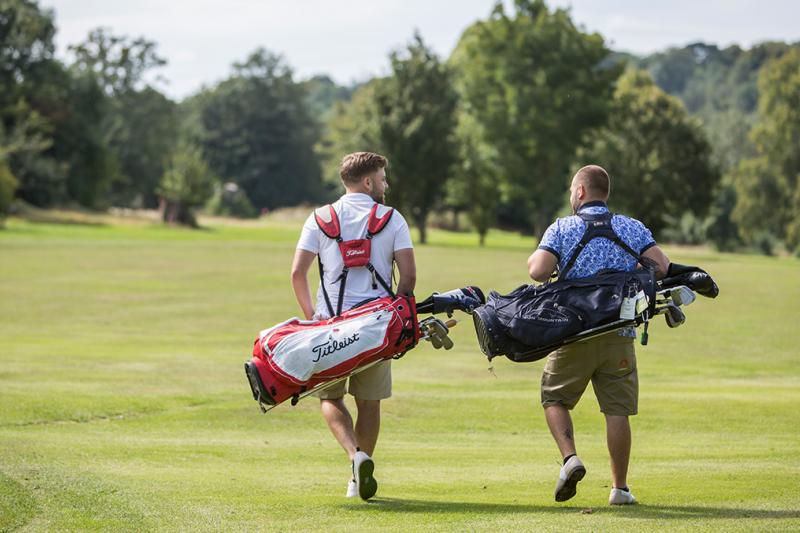 Men walking with golf bags on a golf course