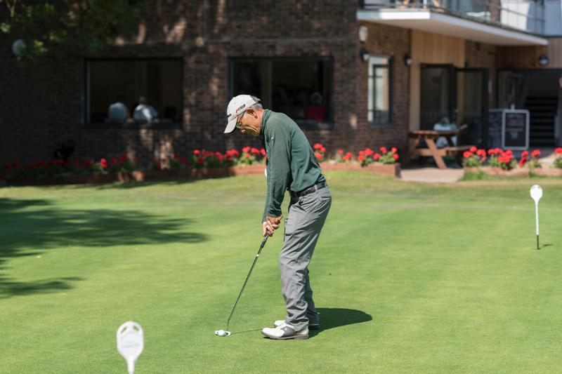 Man practicing putting on a putting green at a golf course