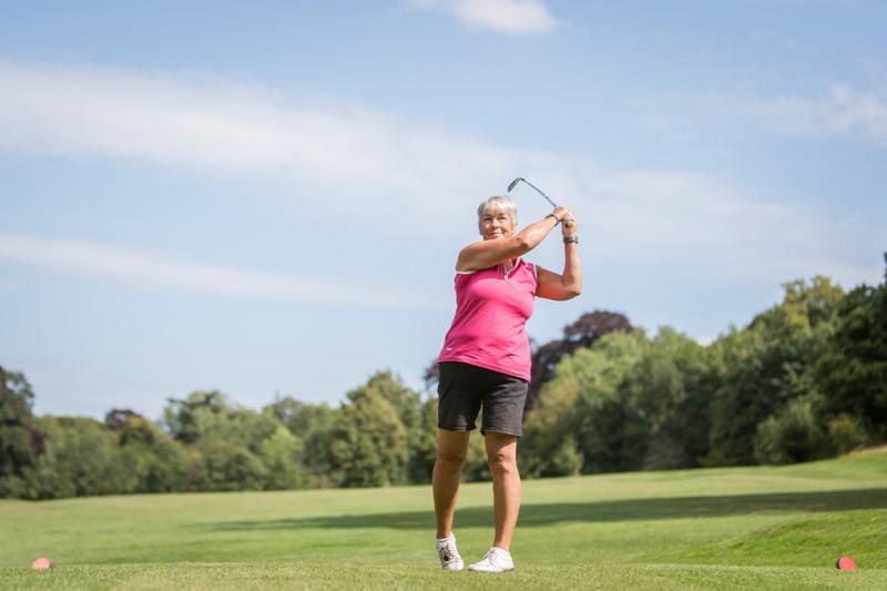 Lady hitting a driver at a golf course