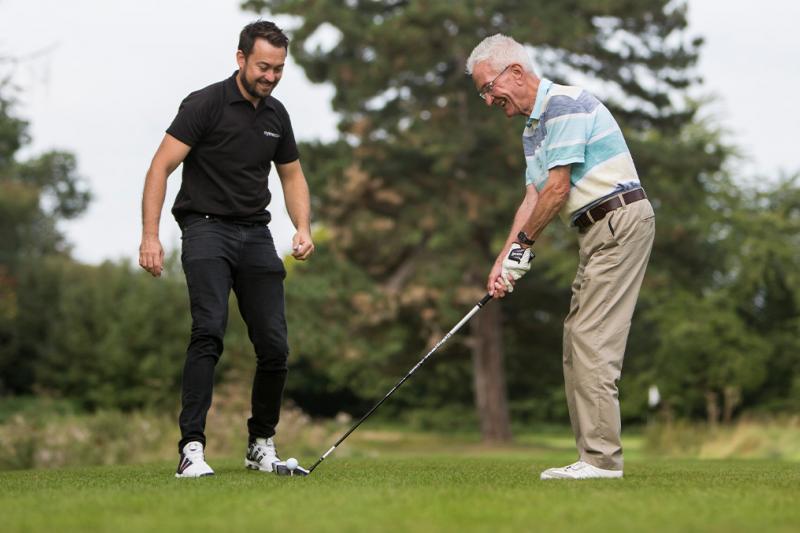 Man smiling on a tee having a golf lesson