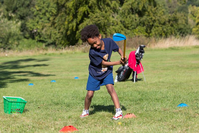 A young boy hitting a golf ball in a junior golf lesson