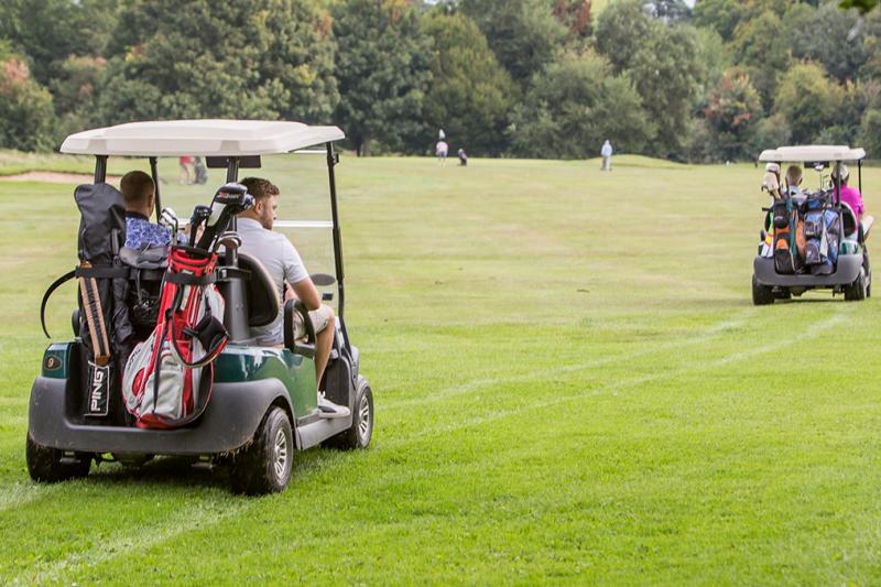 Golfers driving golf buggies