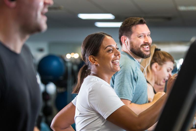 Man and woman laughing on a treadmill at the gym