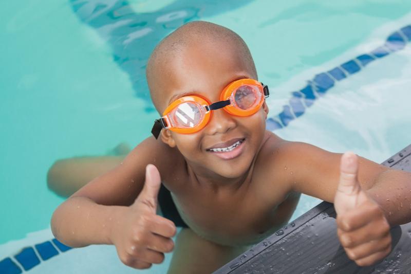 Young boy with thumbs up in the swimming pool