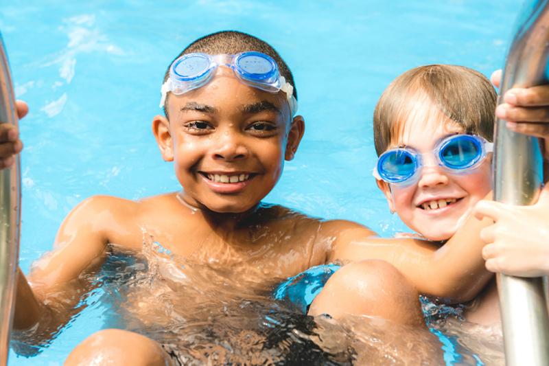 Two young boys having fun by the steps in a swimming pool